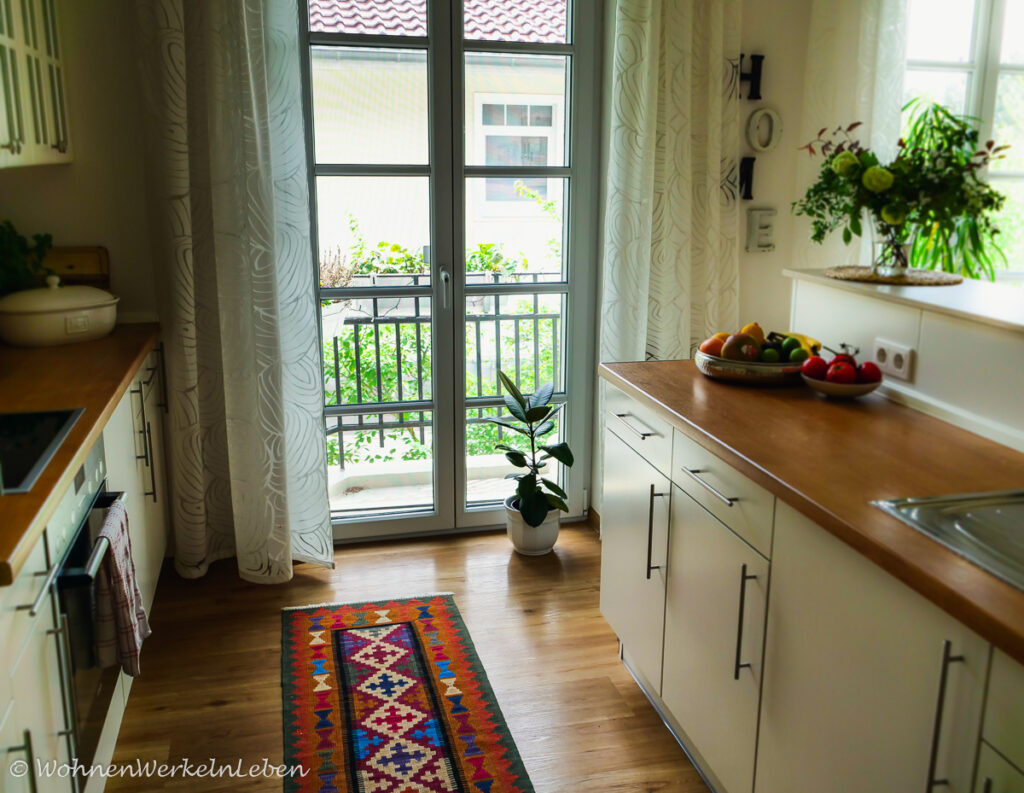 Dekorative, weiße Küche mit Holzarbeitsplatte und Obstschale