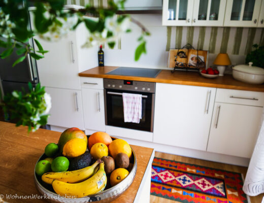 Weiße offene Küche mit Boho Teppich und Obstschale