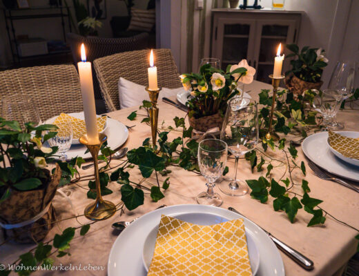 Weihnachtliche Tischdekoration mit Efeu, Christrosen und goldenen Kerzen