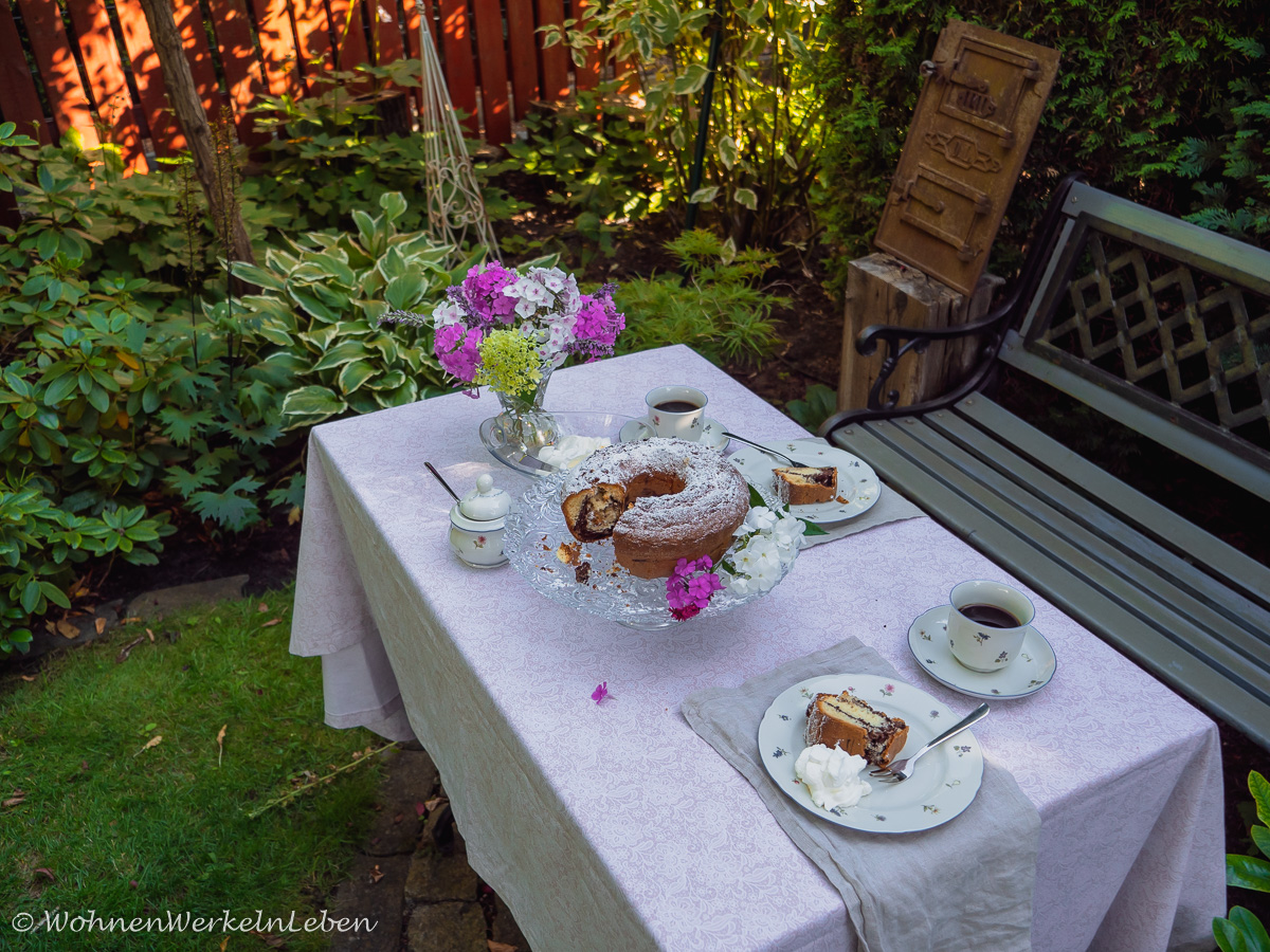 Sommerliche Tischdeko mit frischen Blumen in rosa und weiß und Gugelhupf (Kuchen)